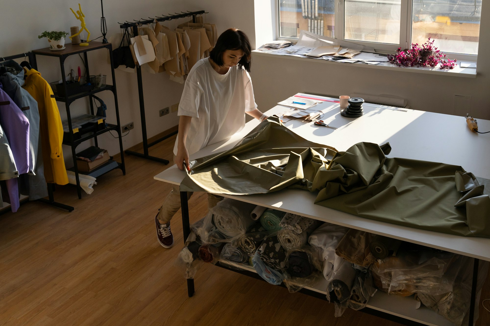 Female dressmaker sew new collection in workshop of fashionable fabric on working table in atelier